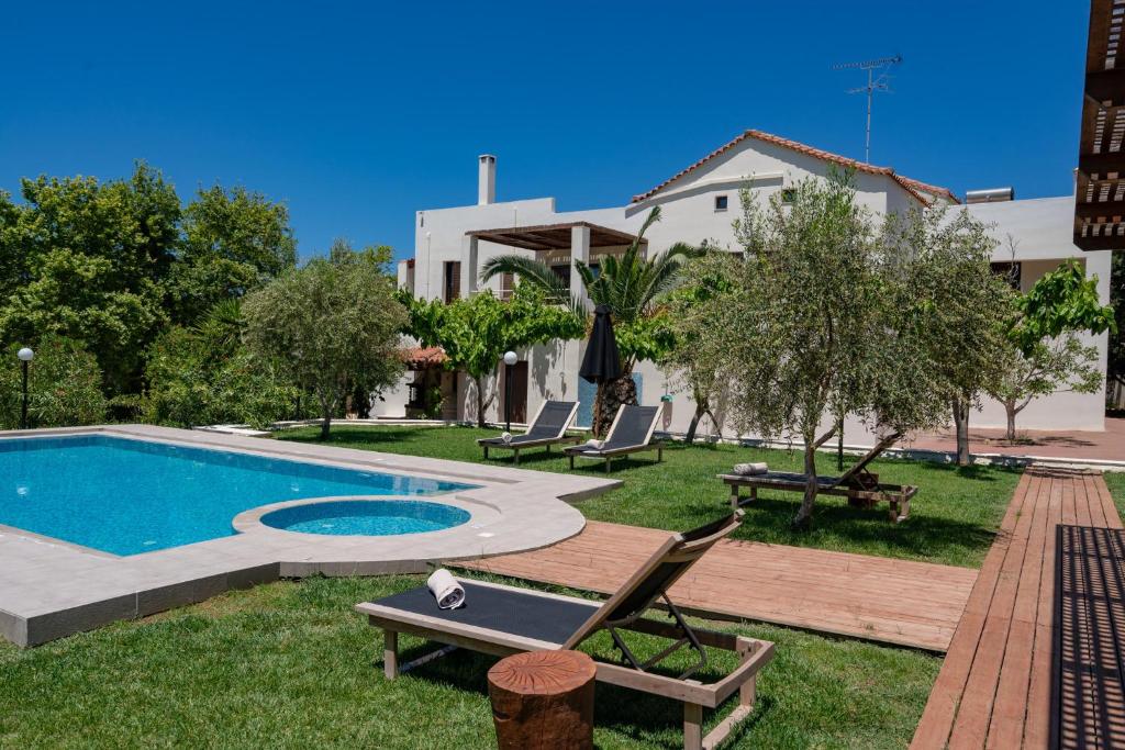 een achtertuin met een zwembad en stoelen en een huis bij Villa Nostos in Prínos