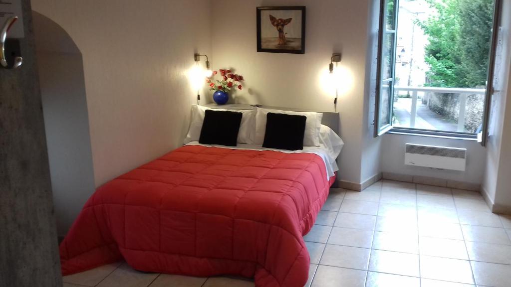 a bedroom with a bed with a red comforter and a window at Le Petit Dyke in Le Puy en Velay