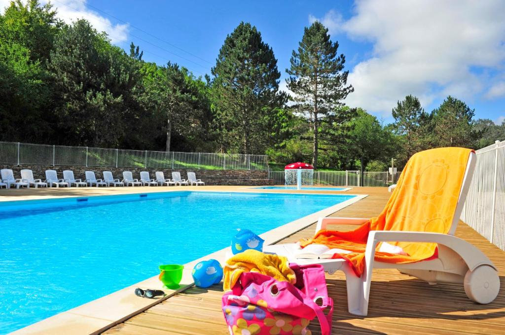 una piscina con chaise longue accanto alla piscina di Résidence Goélia Les Cottages du Lac a Coly