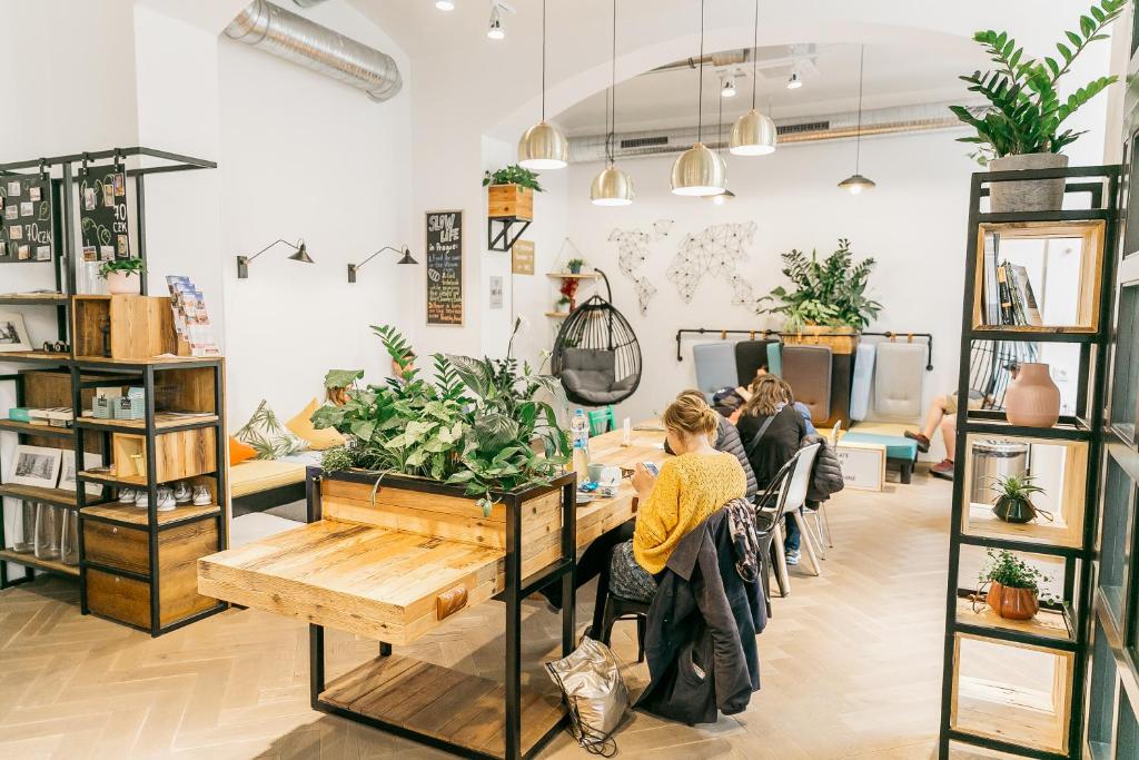 een vrouw aan een tafel in een kamer met planten bij Prague Dream Hostel in Praag