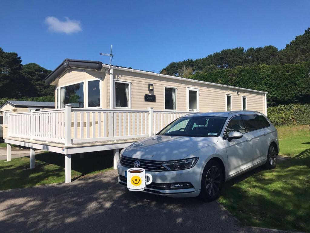 a car parked in front of a house with a cup of coffee at Luxury Holiday Caravan Home in Newquay