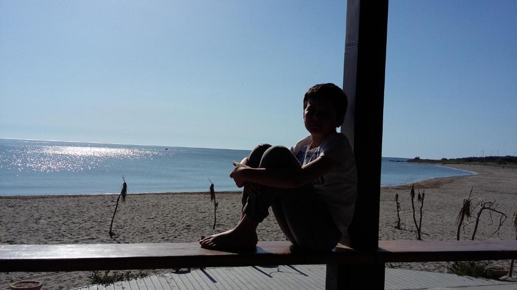 a woman sitting on a porch looking at the beach at Villa Laura in Villaputzu