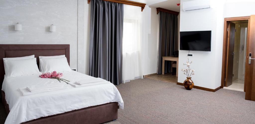 1 dormitorio con 1 cama con sábanas blancas y TV en IPN APARTMENTs, en Podgorica