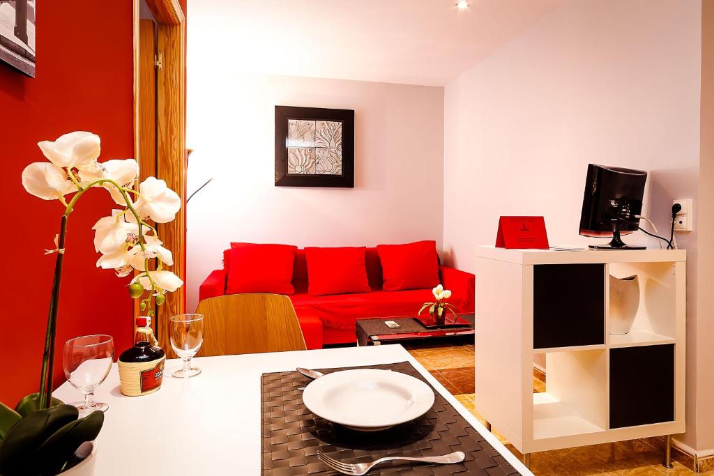 マラガにあるアパルタメントス エル セナセロのリビングルーム(赤いソファ、テーブル付)