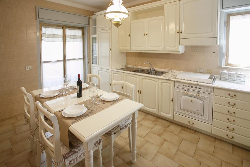 cocina con armarios blancos, mesa y sillas en Ginevra Apartment, en Cefalú