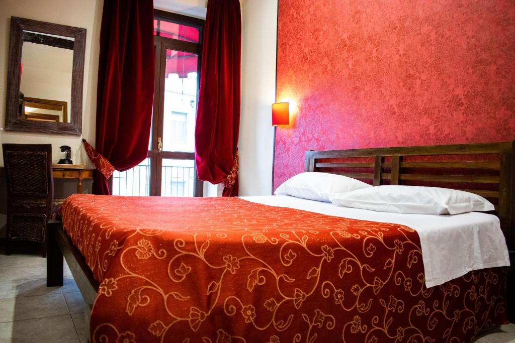 een slaapkamer met een bed met rode muren en een raam bij B&B Muro Torto Lucera in Lucera