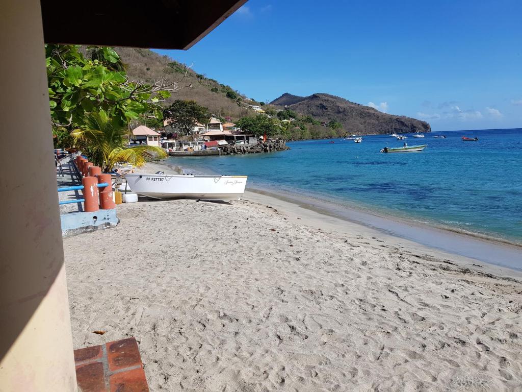 a beach with a boat on the sand and the water at LA YOLE des Caraïbes in Les Anses-dʼArlets