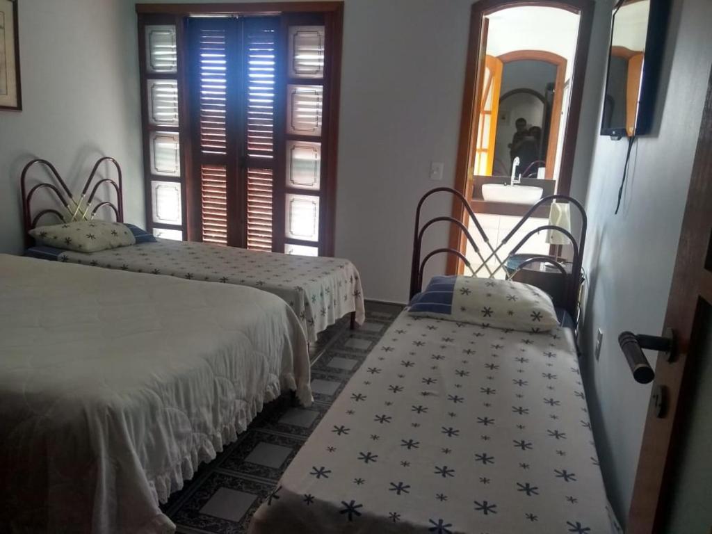 ein Hotelzimmer mit 2 Betten und einem Spiegel in der Unterkunft Casa Condominio Escarpas do Lago em Capitólio MG in Capitólio
