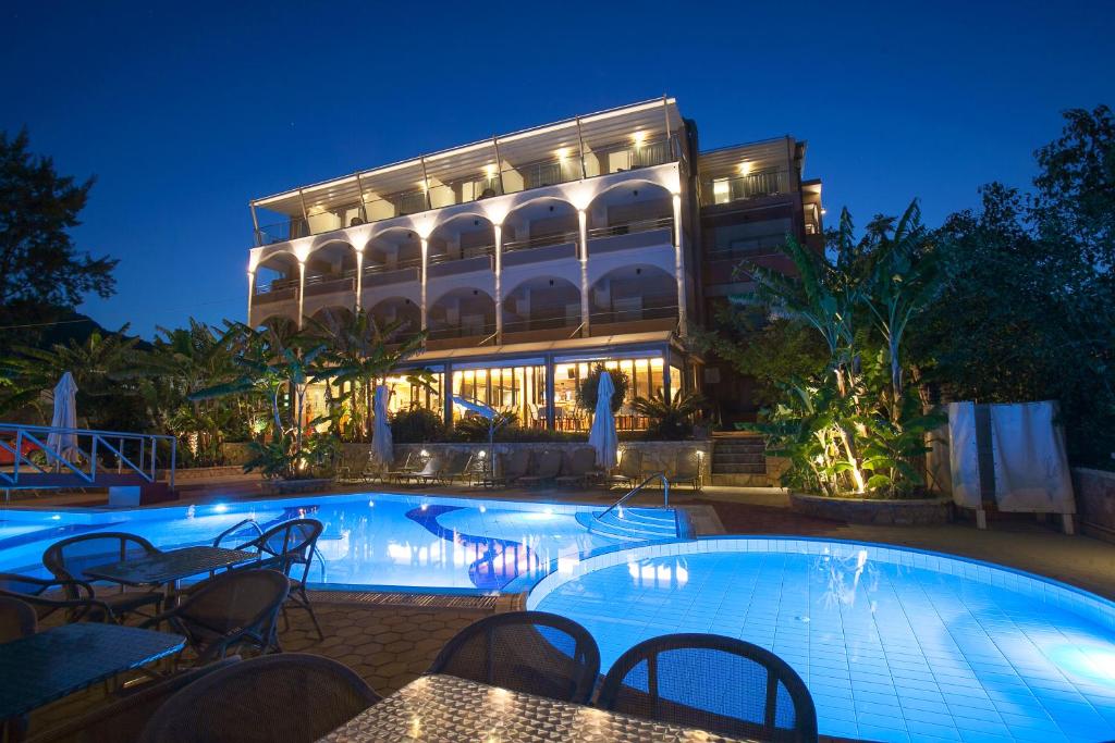 a hotel with a swimming pool in front of a building at Paradise Lost Hotel-Apartments in Tolo