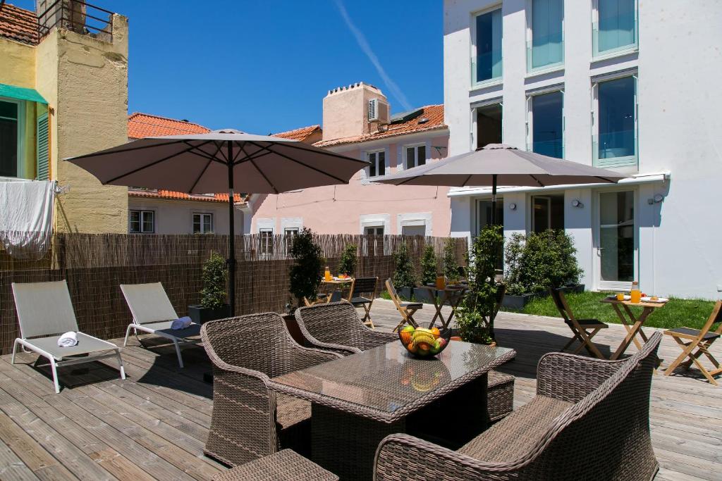 a patio with a table and chairs and umbrellas at ALTIDO Stylish 5BR Apt with big terrace in Principe Real in Lisbon