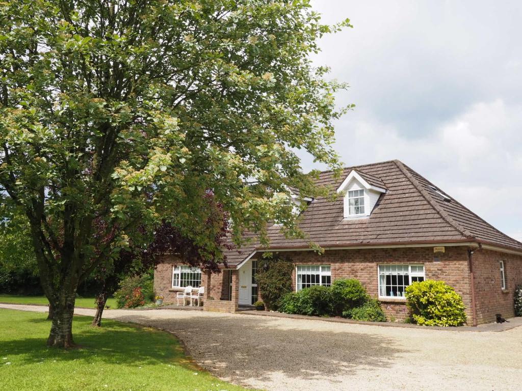 una casa de ladrillo con un árbol delante de ella en Inglewood Lodge B&B en Naas