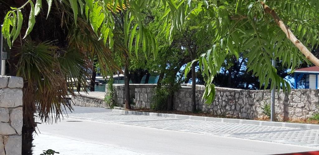 una calle con palmeras y una pared de piedra en Valerija en Tribunj