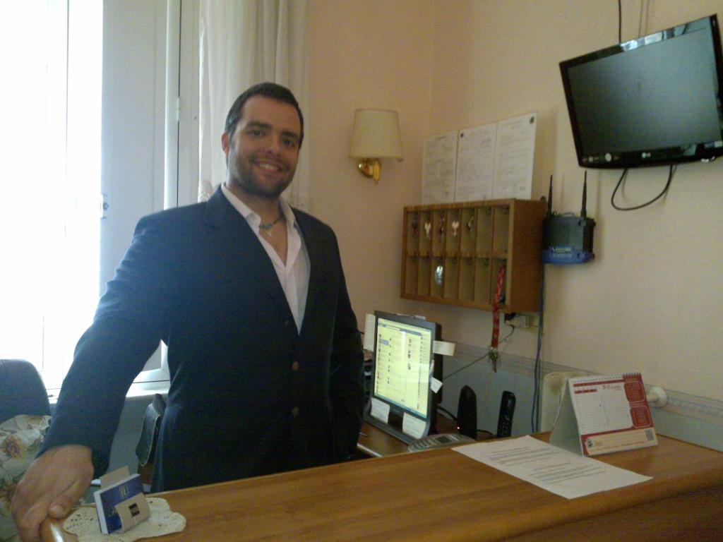 un hombre parado en un escritorio en una habitación en Hotel Lazzari en Roma