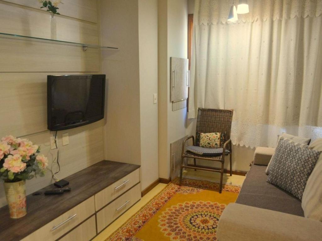 a living room with a tv and a couch and a chair at LOCAR-IN GRAMADO - Residencial Benetti in Gramado