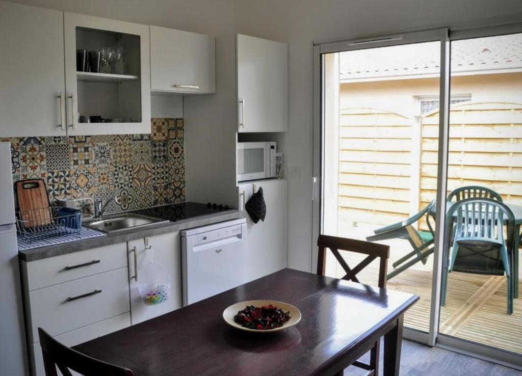 a kitchen with a table with a bowl of fruit on it at La Hume Vacances in Gujan-Mestras