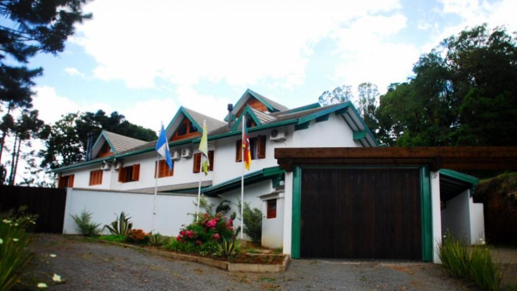 a white house with a garage at Motel Tentação (Adult Only) in Canela