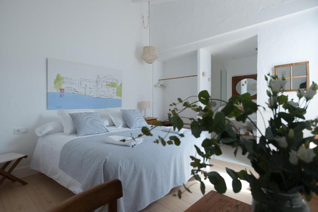 a white bedroom with a bed and a plant at HOTEL ANHEL in Ferreries