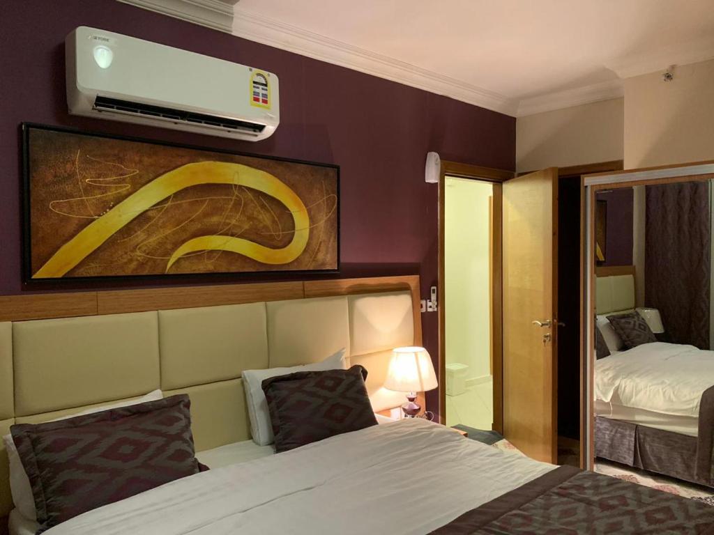 a hotel room with a bed and a tv on the wall at Altelal Apartment in Makkah