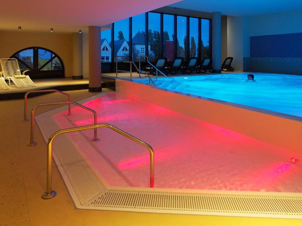 a large swimming pool with red lights in a building at Kurhotel zu Heringsdorf in Heringsdorf