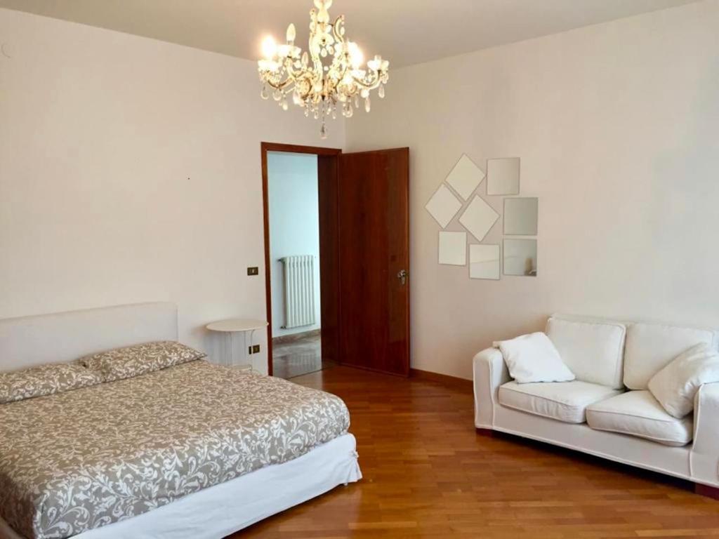 a bedroom with a bed and a couch and a chandelier at Casa Mamma Mia in Fiesso dʼArtico