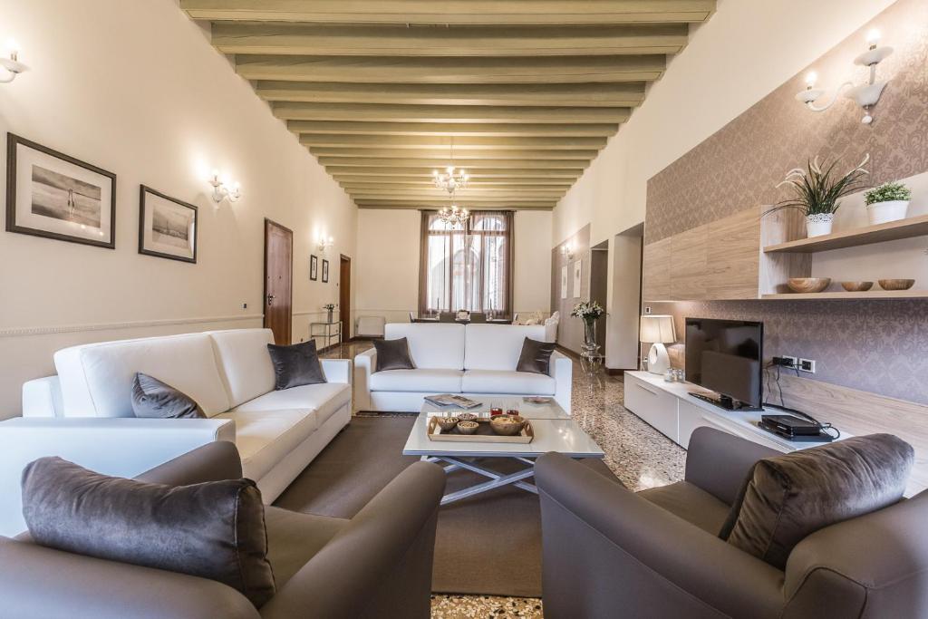 een woonkamer met witte banken en een tv bij Ca' del Monastero 4 Collection Apartment up to 8 Guests with Lift in Venetië