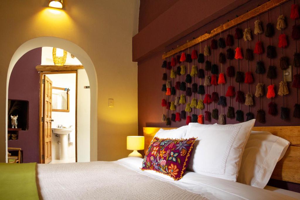 1 dormitorio con 1 cama y una pared con zapatos en Casa de La Chola, en Ollantaytambo