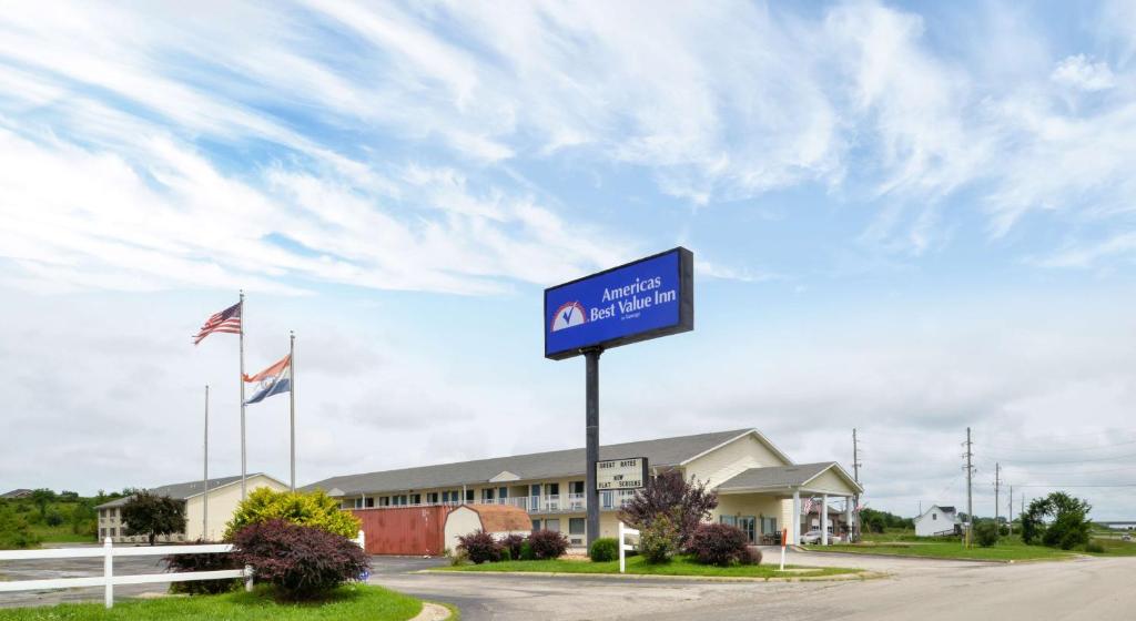 a blue sign in front of a building with flags at Americas Best Value Inn Knob Noster in Knob Noster