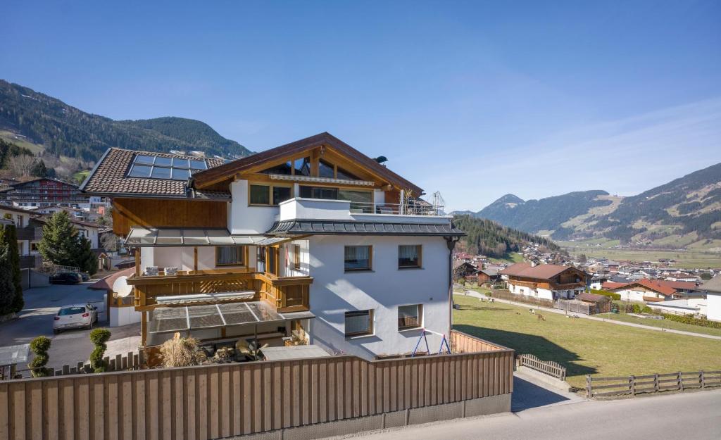 a white house with a wooden fence and mountains at Apartments Gondelspaß in Fügen