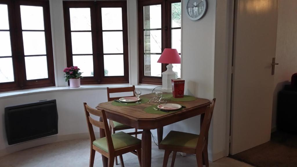 une table à manger avec deux chaises et une horloge dans l'établissement Appart-charme-Aix, à Aix-les-Bains