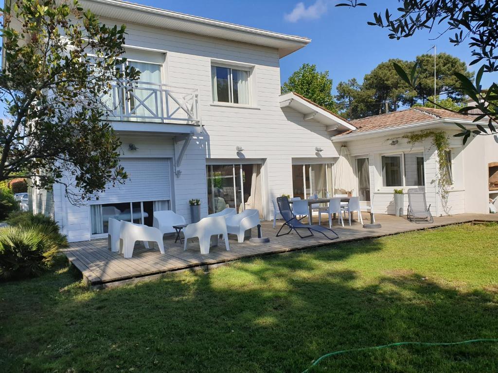 une maison avec une terrasse dotée de chaises et de tables blanches dans l'établissement La Maison Blanche, à Andernos-les-Bains