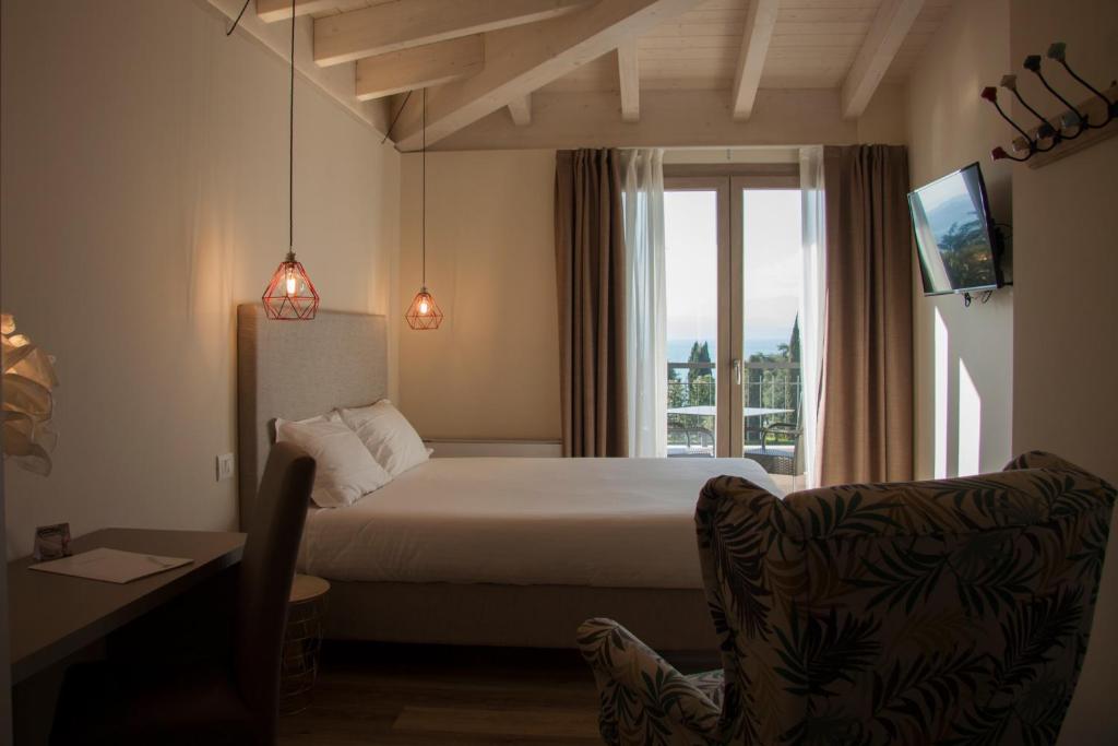 a bedroom with a bed and a window and a chair at Hotel Berta in Desenzano del Garda