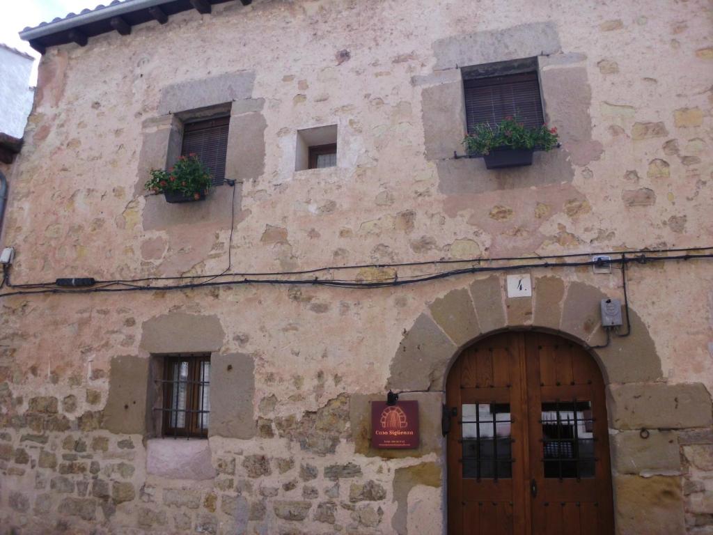 Casa Sigüenza في سيغوينزا: مبنى حجري قديم مع نافذتين وباب
