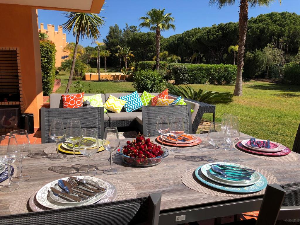 uma mesa de madeira com pratos e copos de vinho em Casa de Férias Vila Sol Golf em Quarteira