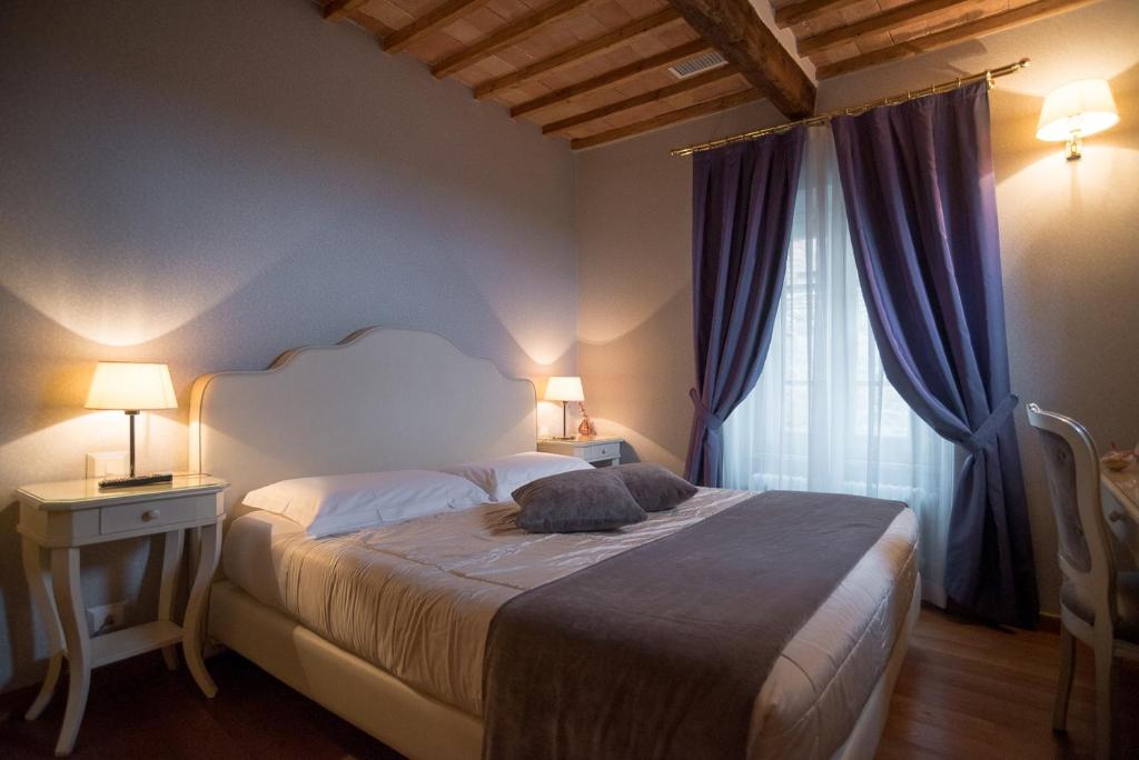 a bedroom with a large bed with two lamps and a window at Le Camere Del Ceccottino in Pitigliano