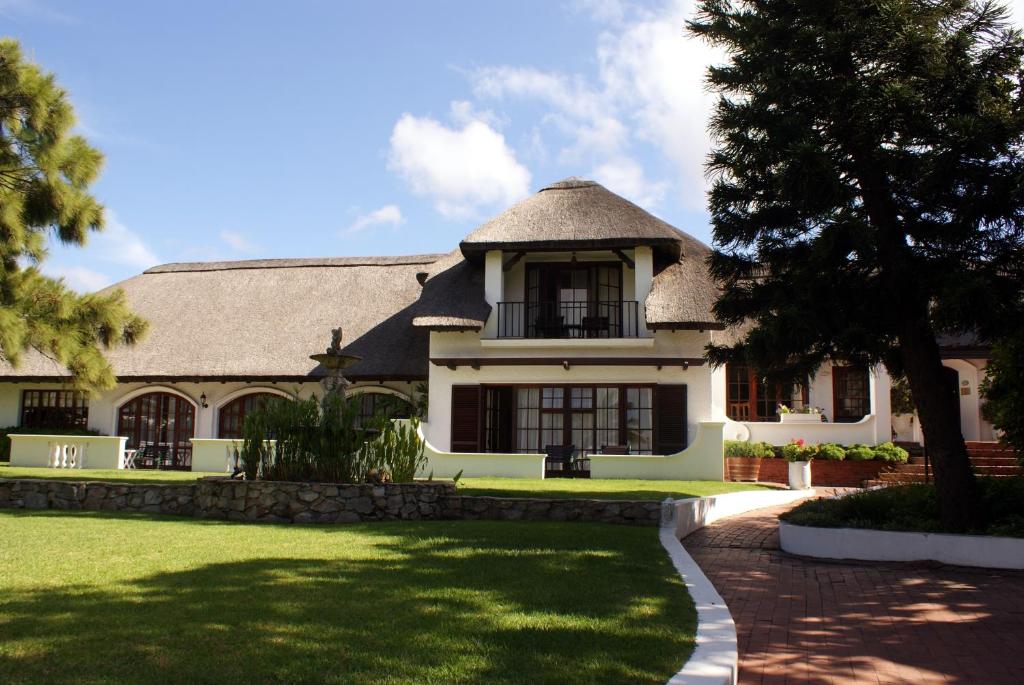 una grande casa bianca con tetto di gambero di Whale Rock Luxury Lodge a Hermanus