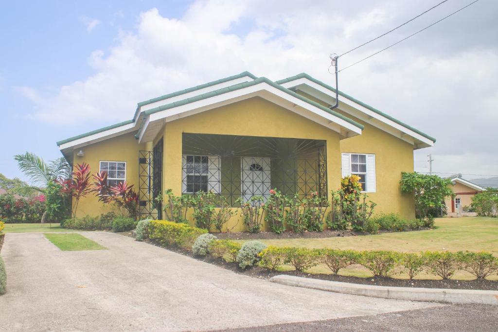 a yellow house with a pathway in front of it at Hibiscus Villa @ DraxHall in Mammee Bay