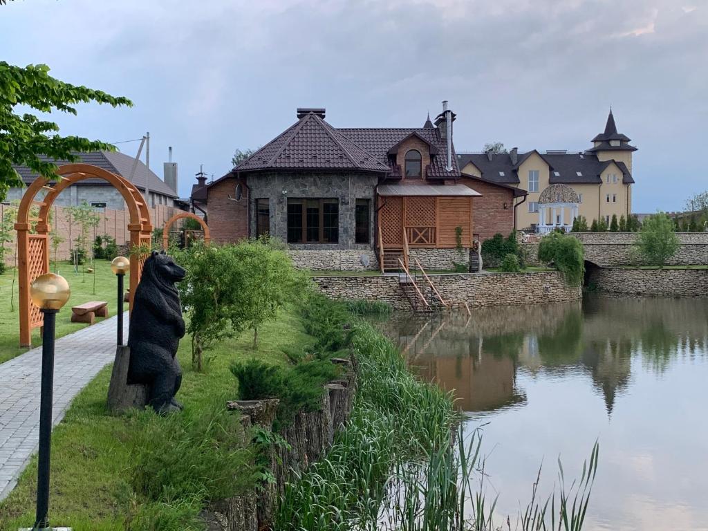 une statue d'un ours assis à côté d'une rivière dans l'établissement Готельно-ресторанний комплекс Прованс парк, à Potchaïv