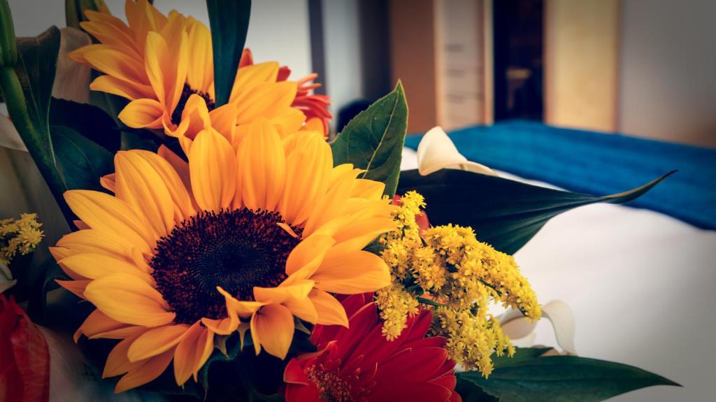 a bouquet of sunflowers and other flowers on a bed at Taormina Panoramic Hotel in Taormina