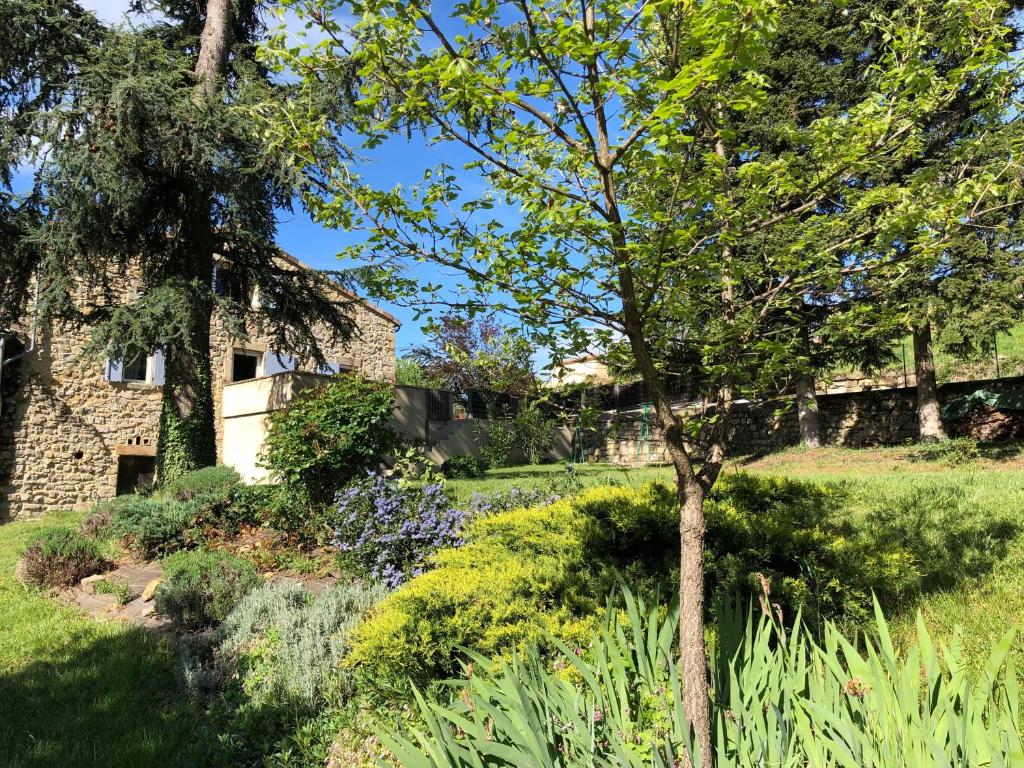 un jardin en face d'une maison en pierre dans l'établissement La Magnanerie ***, à Vesseaux