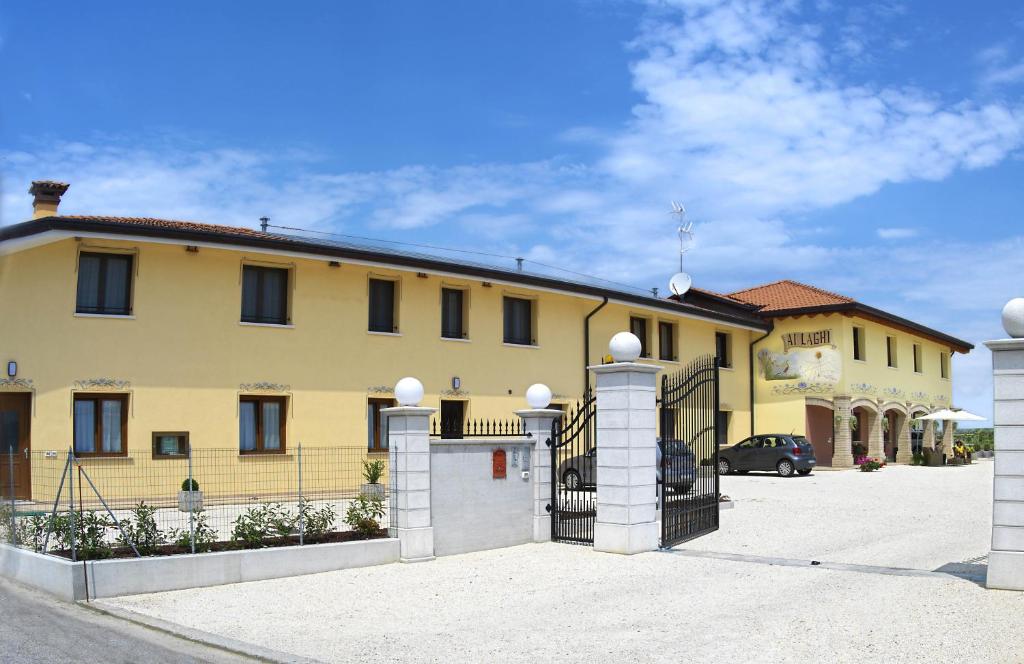 a large yellow building with a gate in a parking lot at Agriturismo Ai Laghi in Pocenia