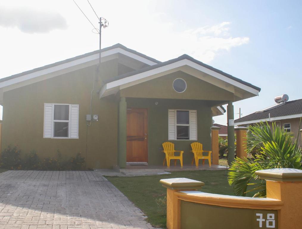a green house with two chairs in front of it at Draxhall Counytry Club Stays in Mammee Bay