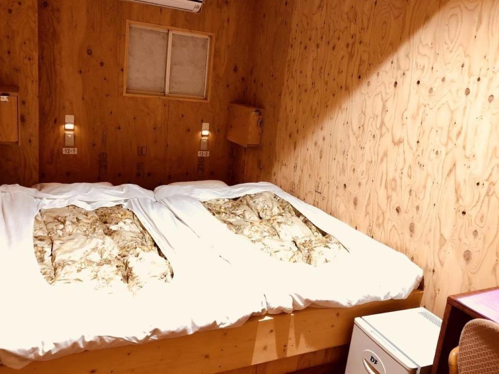 Bett in einem Zimmer mit einer Holzwand in der Unterkunft Guesthouse Otaru Wanokaze double room / Vacation STAY 32211 in Otaru