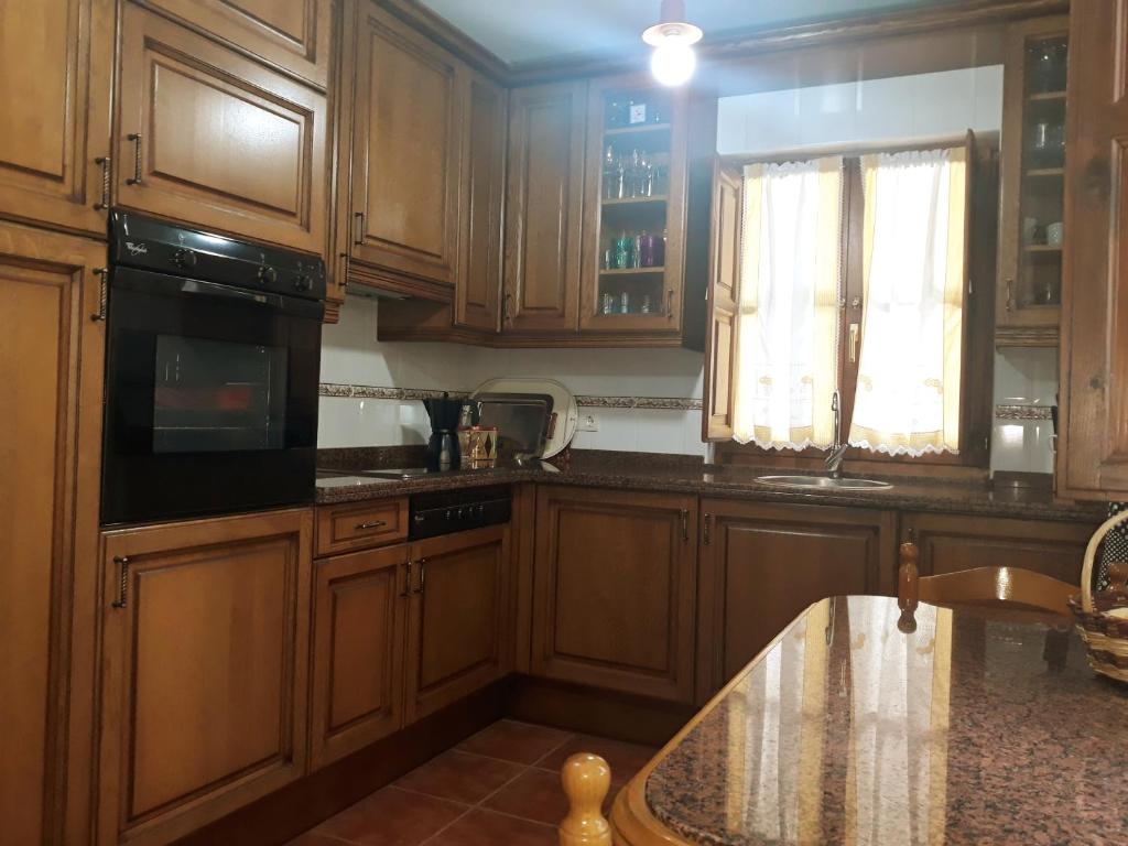cocina con armarios de madera, fregadero y ventana en Casa Rural La Llosica, en Ribadesella