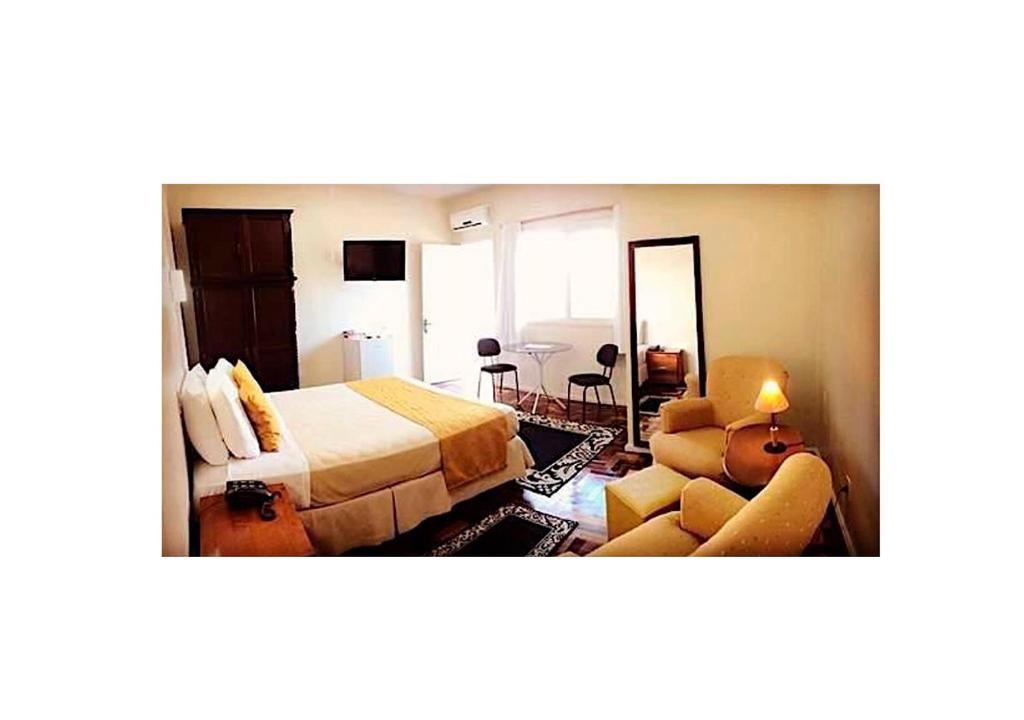 a hotel room with a bed and a living room at Hotel Ibiá in Montenegro