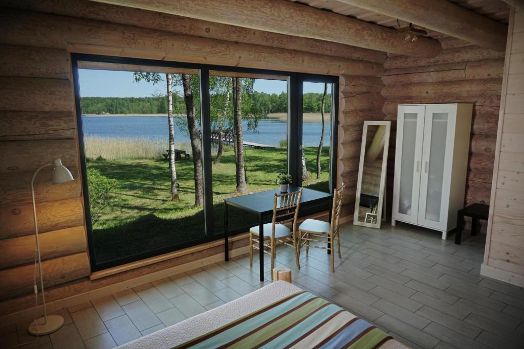 een kamer met een tafel en uitzicht op een meer bij Du Horizontai in Molėtai