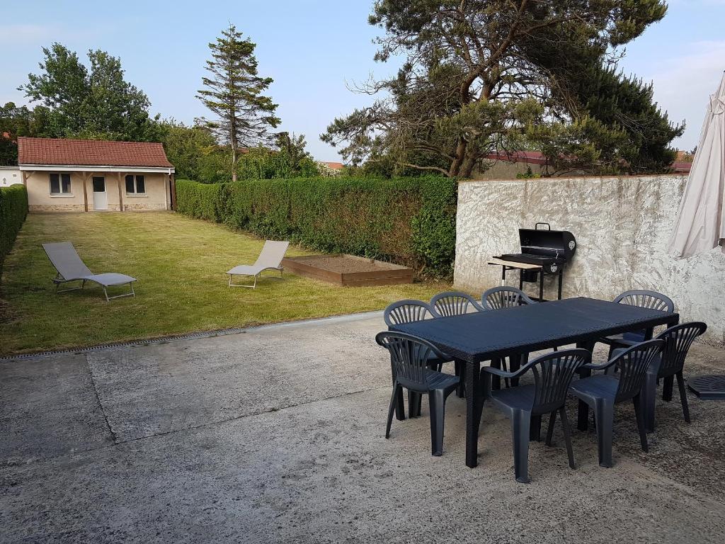 une table et des chaises noires dans une cour avec un grill dans l'établissement Maison Napoléon, à Wimille