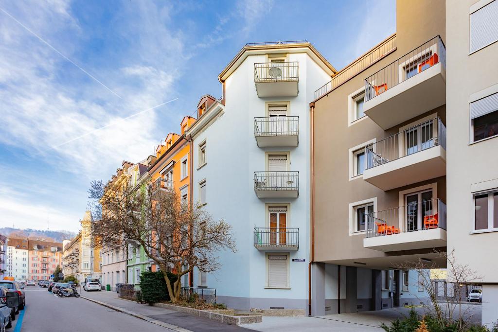 a tall white building with balconies on a street at Swiss Star Zurich Sihlfeld - Self Check-In in Zürich