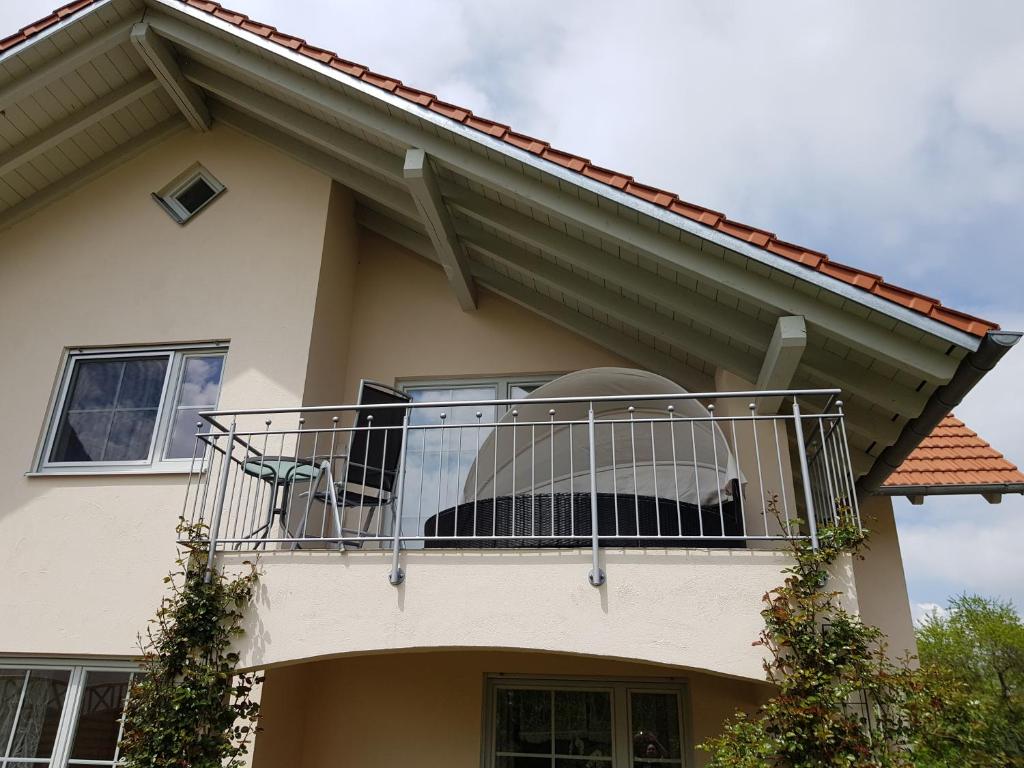 un chien assis sur un balcon d'une maison dans l'établissement Romantik Ferienwohnung am Tor zum Allgäu - Erwachsenenferienwohnung, à Fuchstal