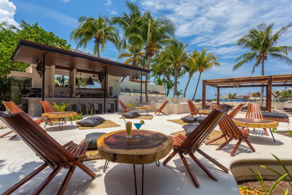 una casa y un patio con sillas y mesas. en Lotus Beach Hotel - Adults Only, en Isla Mujeres
