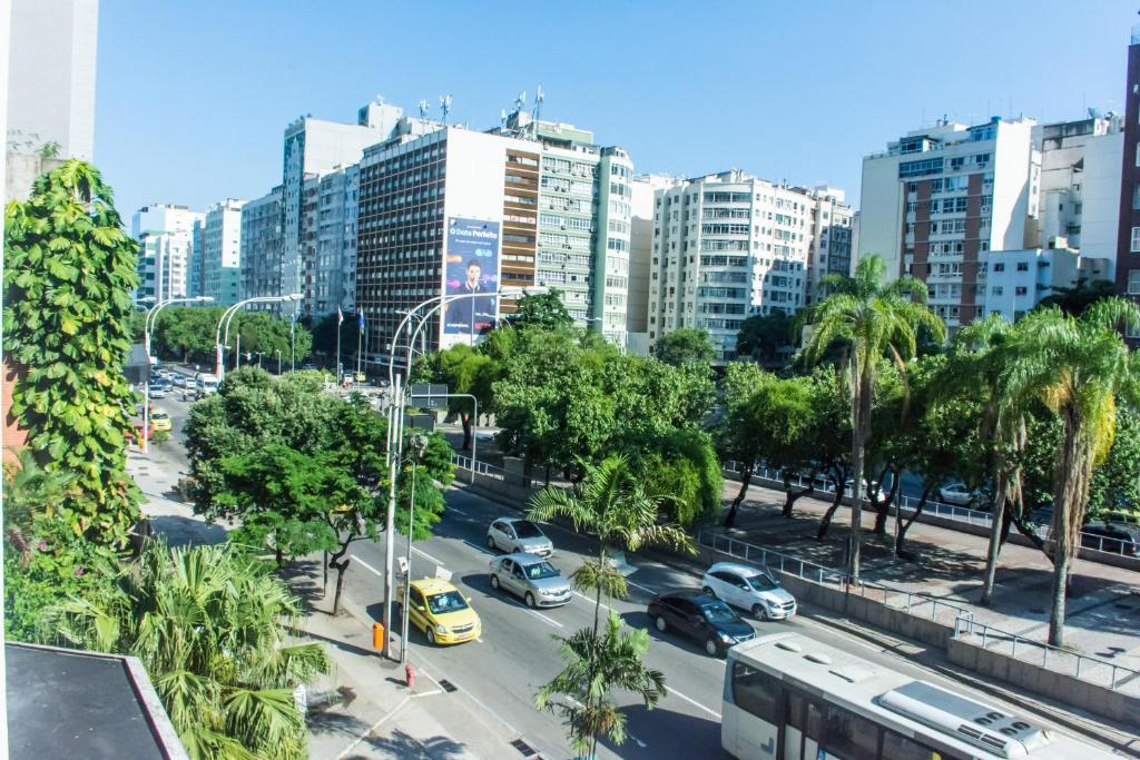 a city street with cars and palm trees and buildings at Apart hotel Copacabana Próximo a praia in Rio de Janeiro